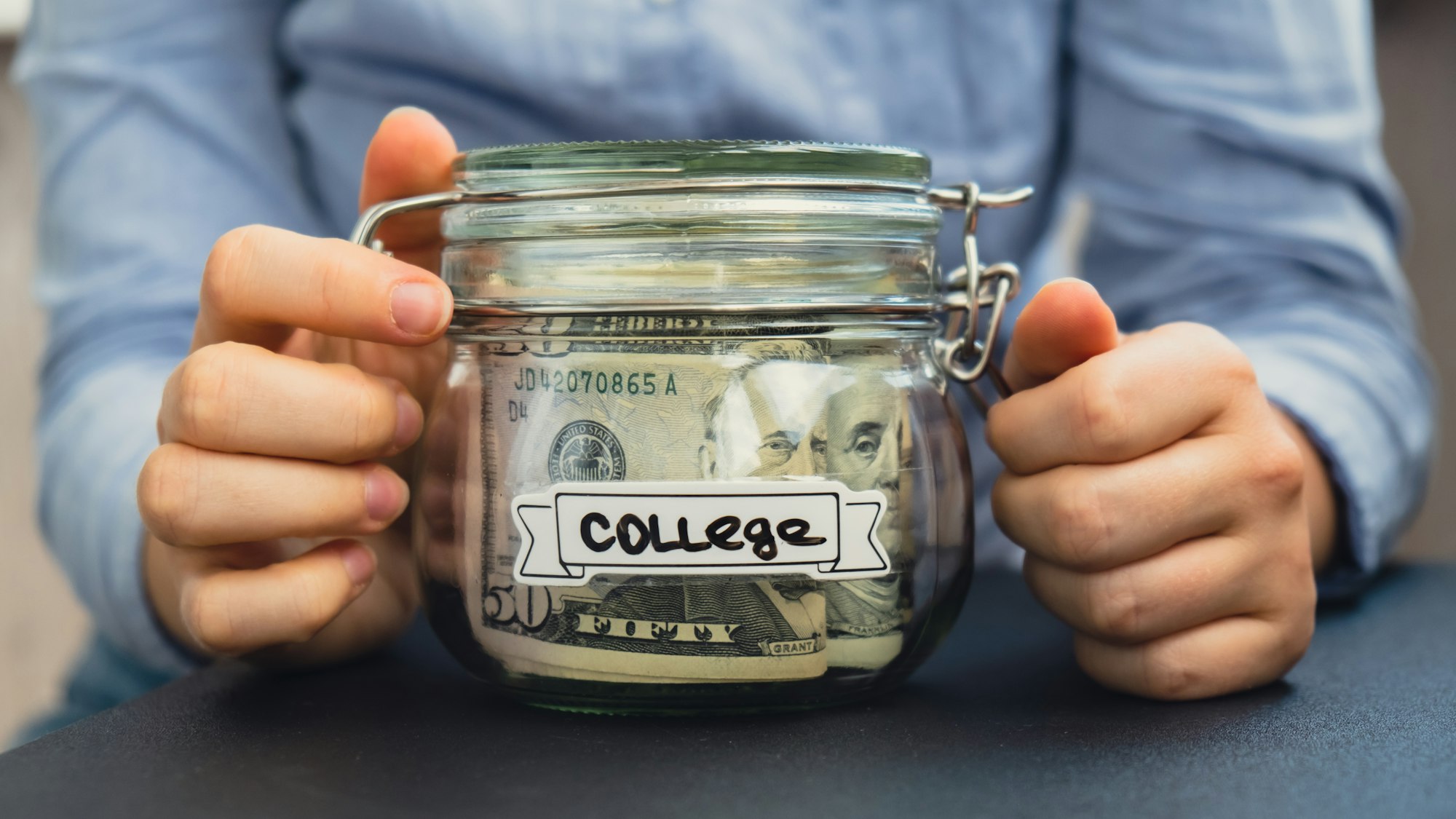 Unrecognizable woman holding Saving Money In Glass Jar filled with Dollars banknotes. COLLEGE